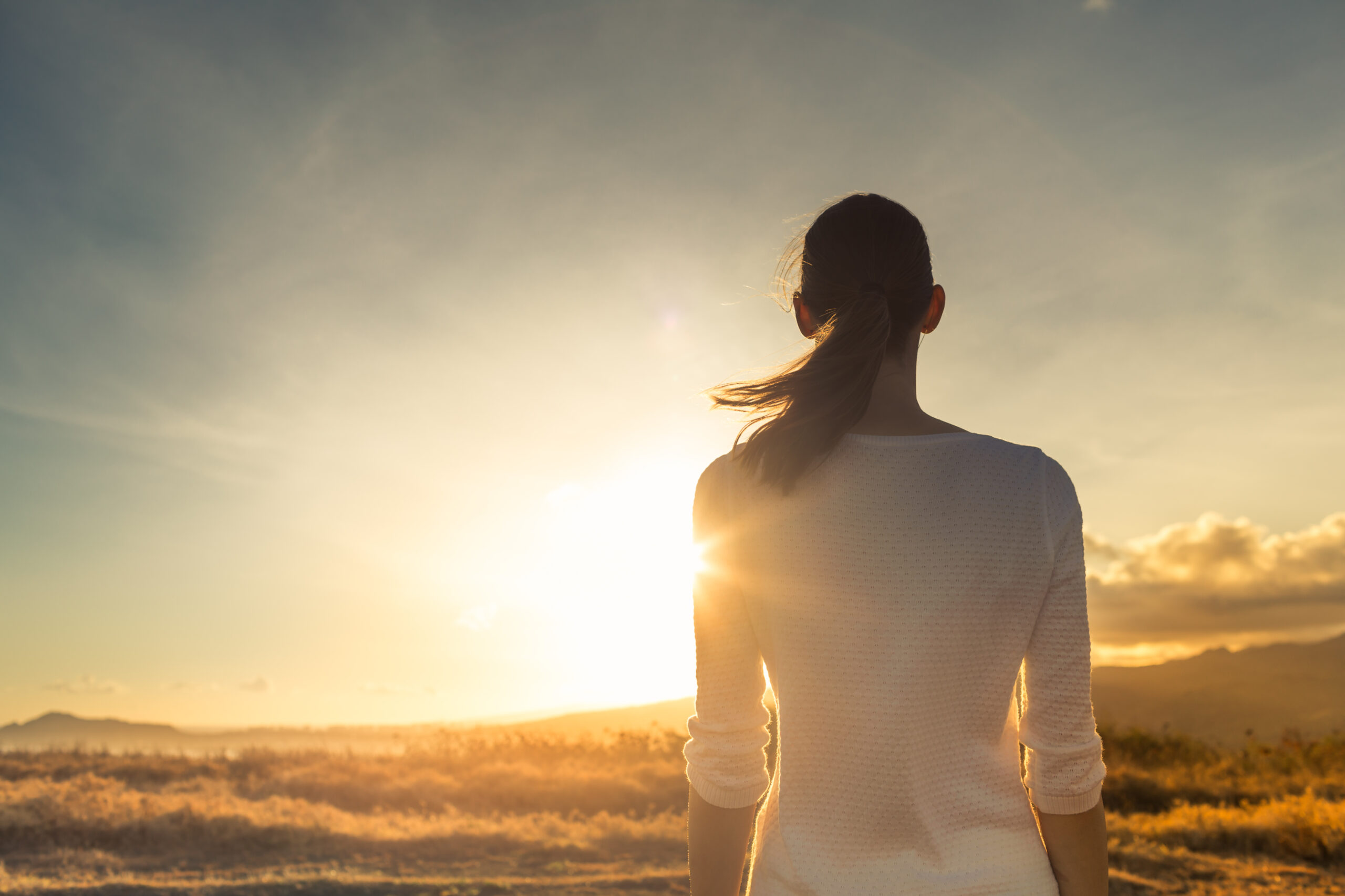 Life is beautiful. Woman standing facing a beautiful golden sunr